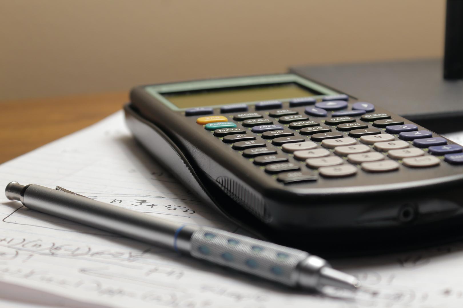 Taschenrechner, Stift und beschriebenes Papier