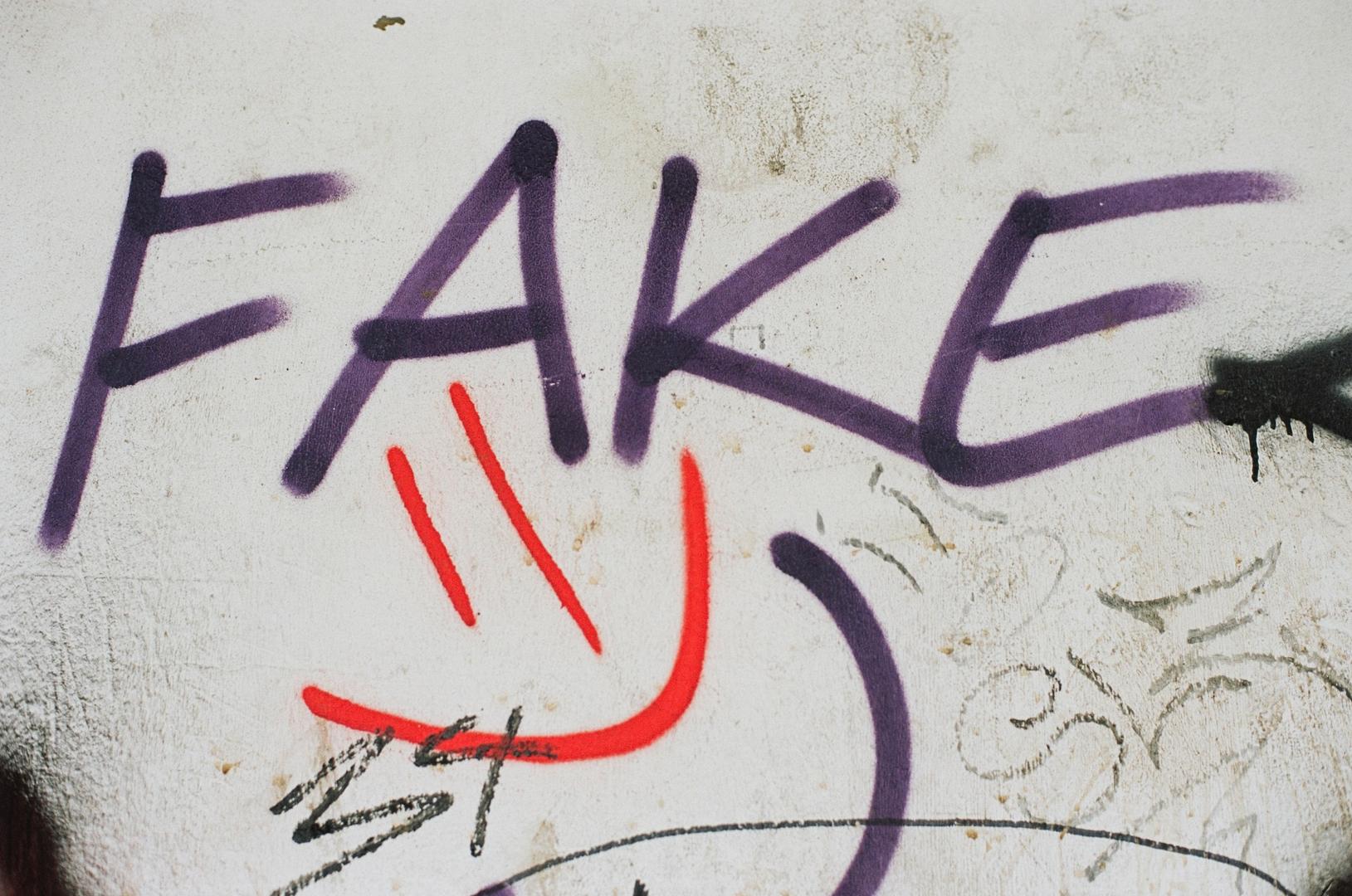einfaches Graffiti mit dem Wort Fake und einem lachenden Smiley
