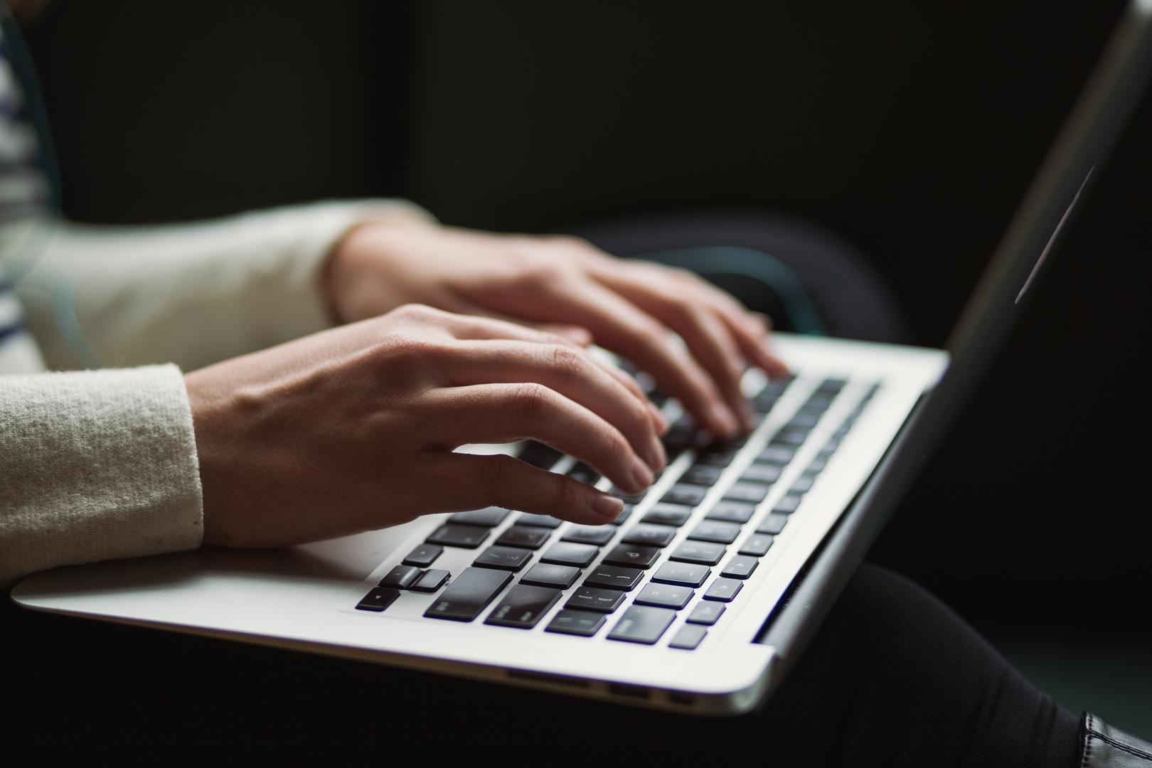 Hände tippen etwas am Laptop ein