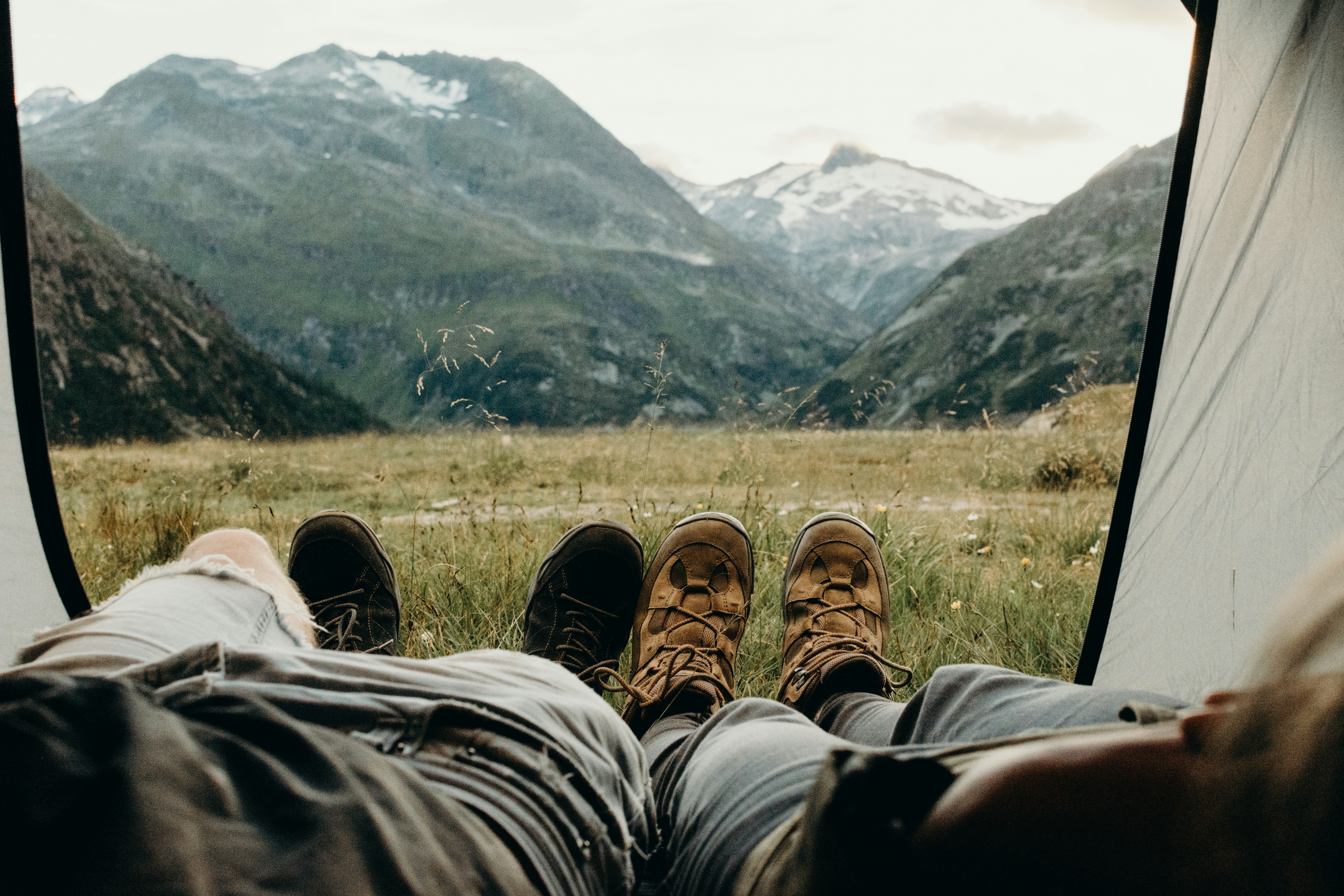 bergige Landschaft, Zelt, zwei Personen, deren Beine aus dem Zelt hängen