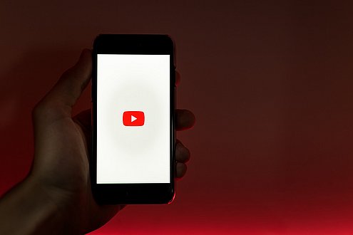 Hand hält Handy mit YouTube Logo