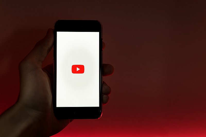 Hand hält Handy mit YouTube Logo