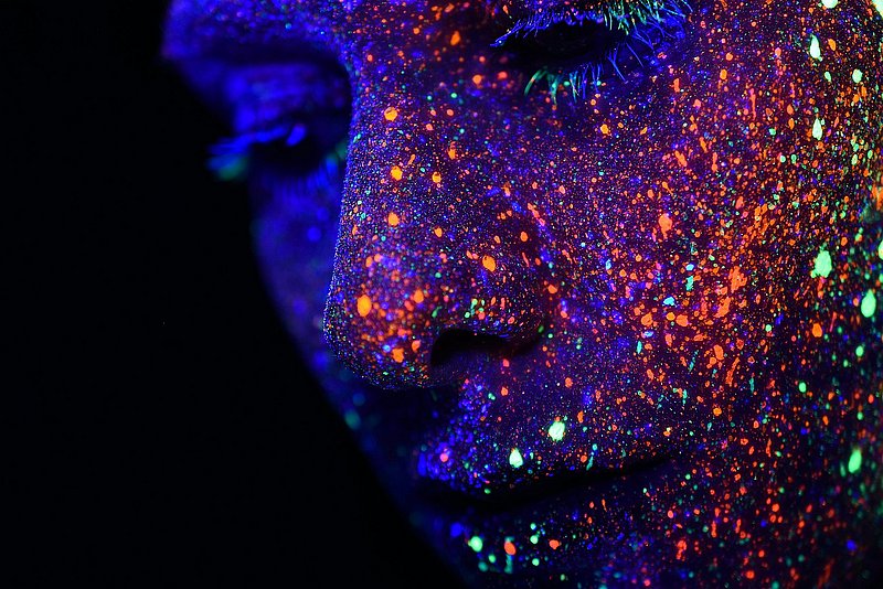 Mensch mit Farbpunkten in Schwarzlicht