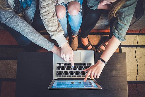 Jugendliche sitzen gemeinsam vor Computer