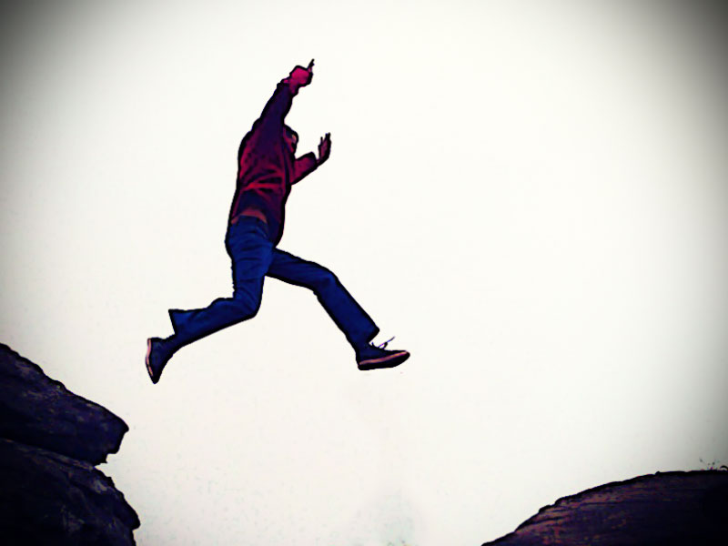 Person springt über Spalte im Fels