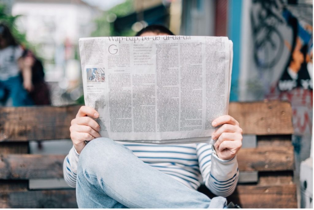 Frau liesst Zeitung auf Parkbank